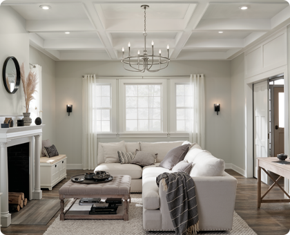 A beautiful living room illuminated evenly by a chandelier, sconces, and recessed lighting.