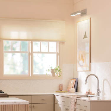 A picture light adds visual interest to the corner of a clean, modern kitchen.