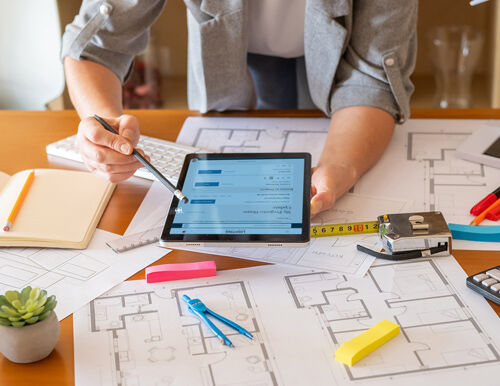 Designer reviewing 2026 lighting plans and budget sheets for value engineering strategies.