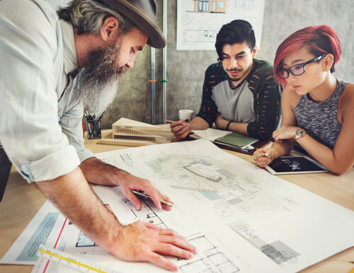 Designer, builder, and architect collaborating on lighting plans around a table