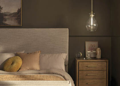 A bedside table lit by a dimmable pendant for varied lighting needs.