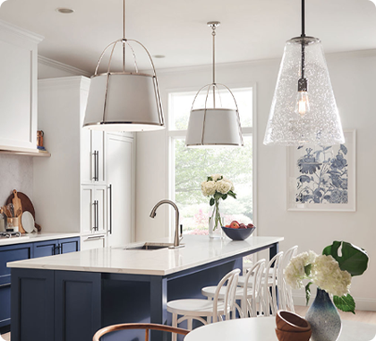 A modern kitchen and dining area illuminated in separate zones by pendant lighting.
