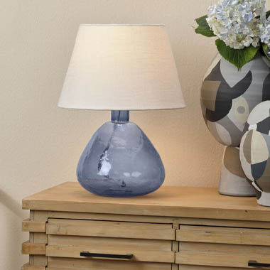 A natural side table and colorful vases illuminated by a simple, attractive glass table lamp.
